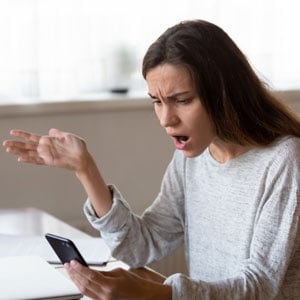  Surprised woman holds cell phone, potentially learning about dischargeable debts - THE LAW OFFICES OF DIANE ANDERSON